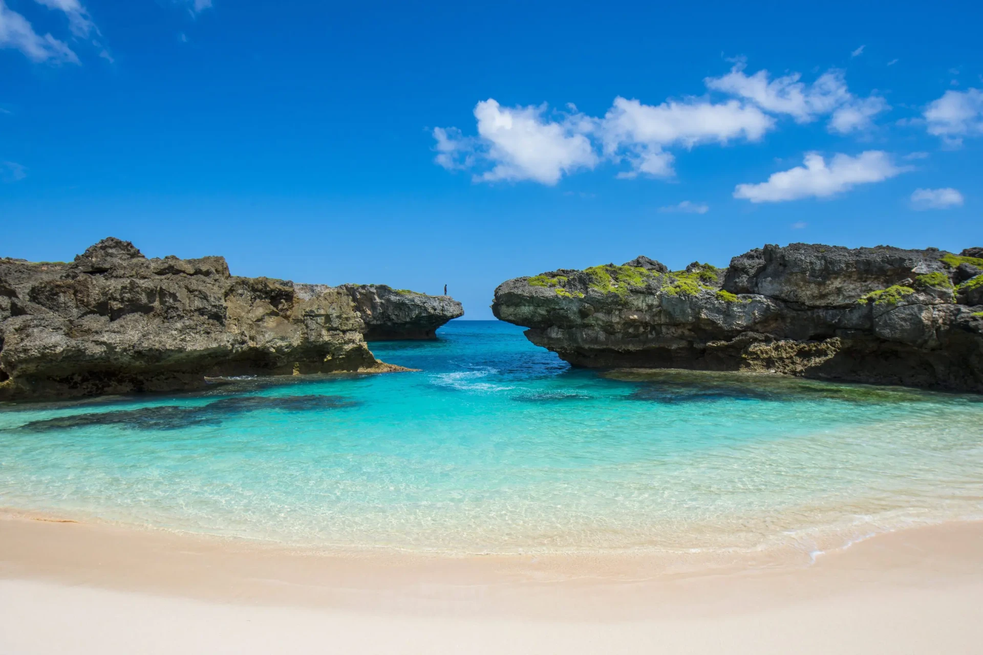 Turquoise cove between rocky headlands on a white sand beach